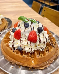 Golden waffle with berry berry cream, chocolate drizzle, mixed berries and fluffy cream at thebrgr cafe